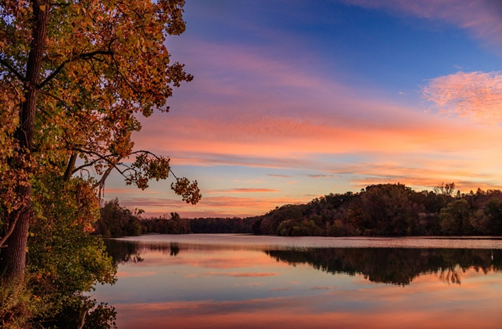 A colorful autumn sunrise is reflected in the Huron River in Ann Arbor, Michigan