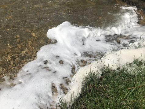 Creamy white foam suspected of containing PFAS on Portage Lake