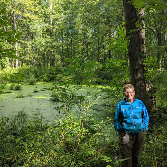 Photo of Kris Olsson standing by a wetland