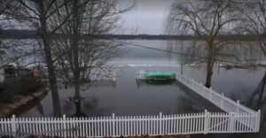 A flooded backyard with a white fence