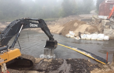 Excavator removing sediment from channel